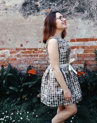 Side view of young woman standing against wall