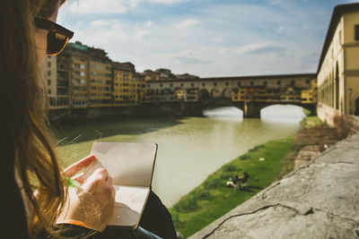 Woman making sketch of ponte vecchio over arno river