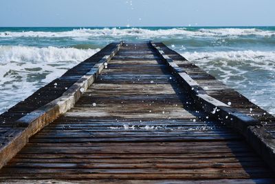 Boardwalk on beach against clear sky