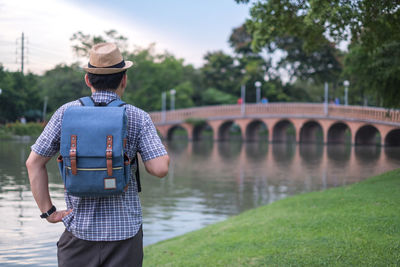 Rear view of man standing on bridge over river