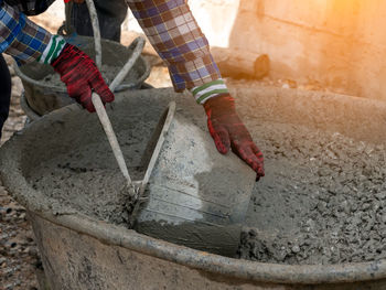 Man collecting cement in bucket while working at construction site