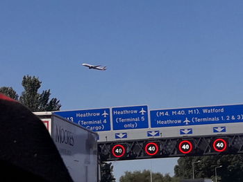 Low angle view of road sign against clear blue sky