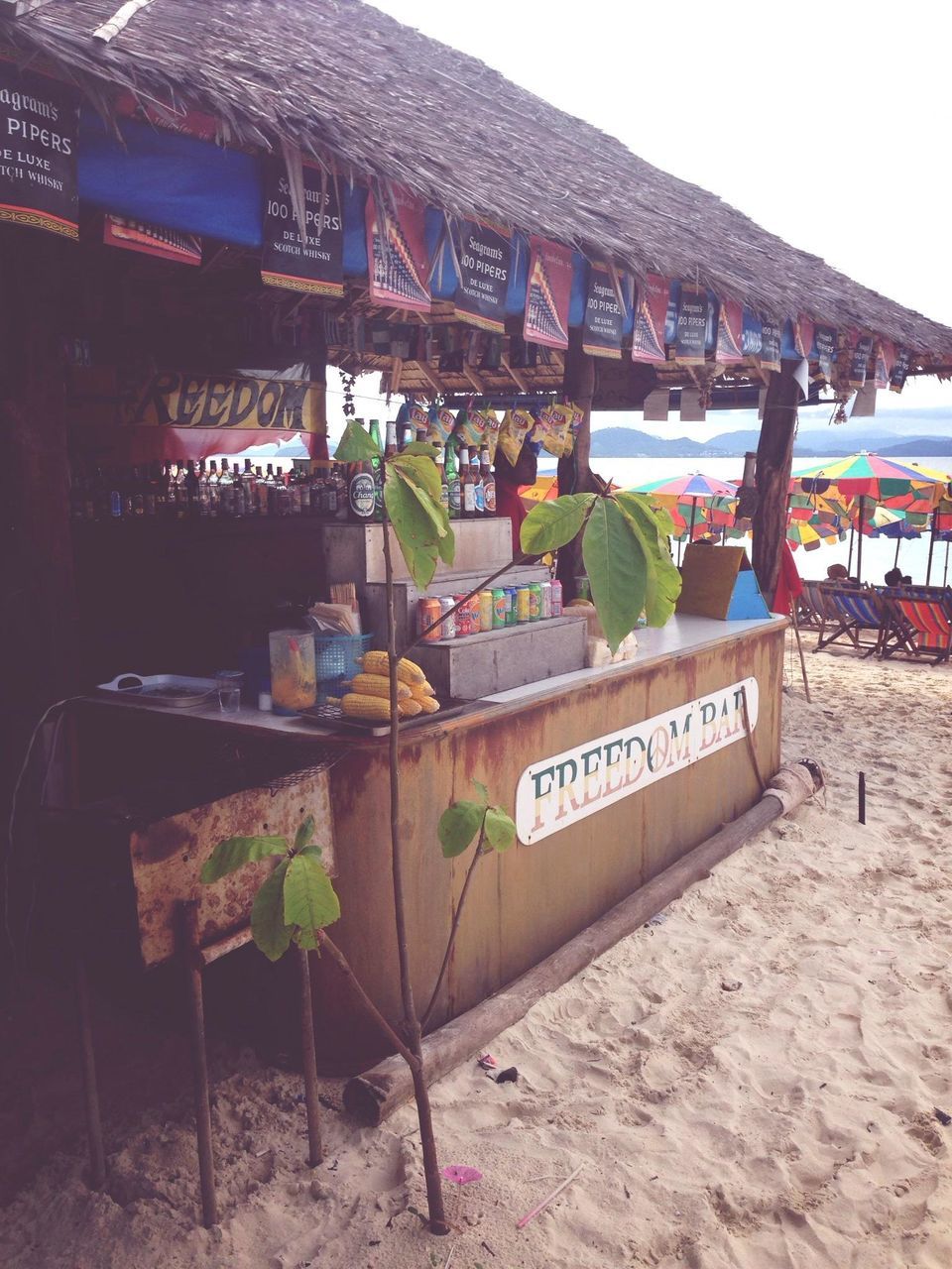 text, beach, western script, water, sand, nautical vessel, boat, built structure, sea, moored, transportation, shore, building exterior, clear sky, communication, architecture, incidental people, mode of transport, outdoors, day