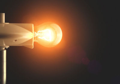 Close-up of illuminated lighting equipment against sky at night