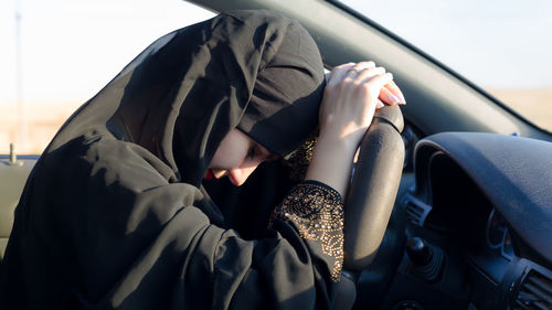 Close-up of sad woman wearing hijab sitting in car