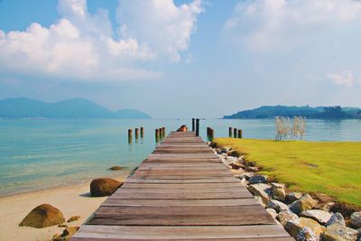 Wooden jetty on pier over sea against sky