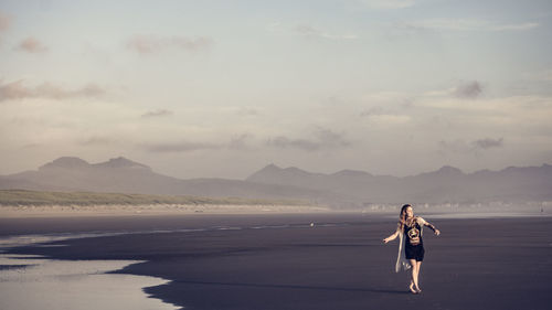 Full length of woman walking at beach against sky