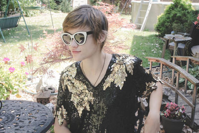 Young woman wearing sunglasses while sitting on chair at park