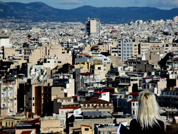 Rear view of woman by cityscape against mountains