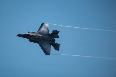 Low angle view of airplane flying against clear blue sky