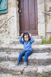 Little handsome baby boy sitting on ancient stone stairs