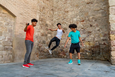 Three afro latin male friends dancing in the street and recording it