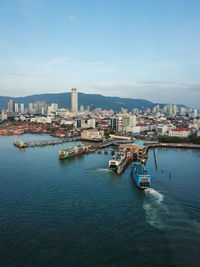 Boats in river by buildings in city against sky