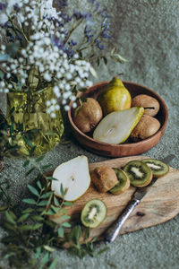 Still life of pear and kiwi on the table with a vase of flowers