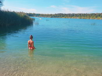 Rear view of young woman in bikini standing in lake