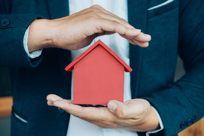 Close-up of man holding red model home