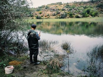 Rear view of man standing by lake