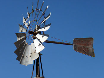 Low angle view of telephone pole against clear blue sky