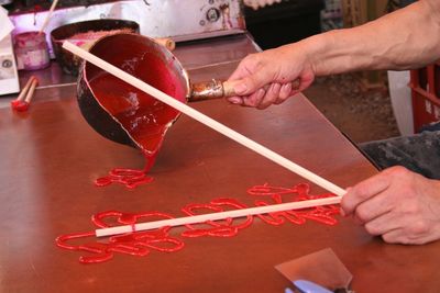 High angle view of person hand pouring red syrup on table