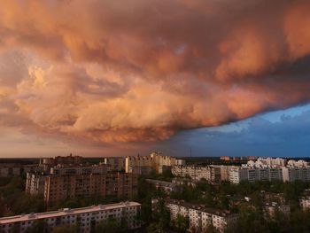 Buildings in city against dramatic sky during sunset