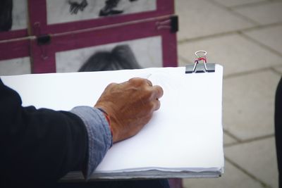 Close-up of hand holding paper on table