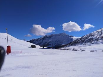 Scenic view of snow covered mountains against blue sky