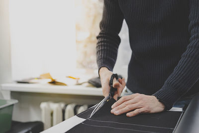 Midsection of man cutting textile in workshop