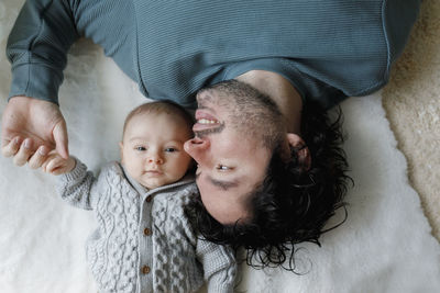 Happy father lying on bed with baby boy at home