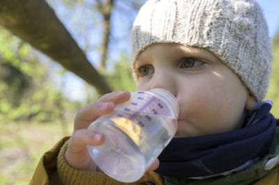 Cute caucasian boy is drinking water from a bottle outdoors