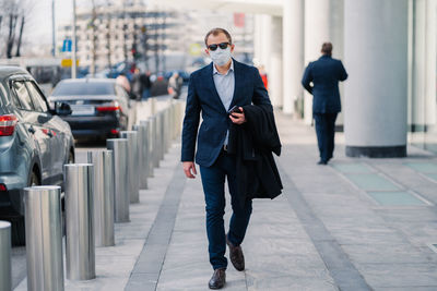 Businessman wearing mask walking in city