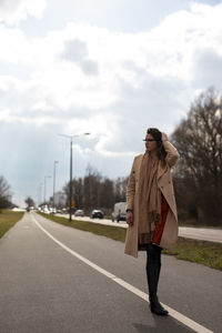 Full length of woman standing on road against sky