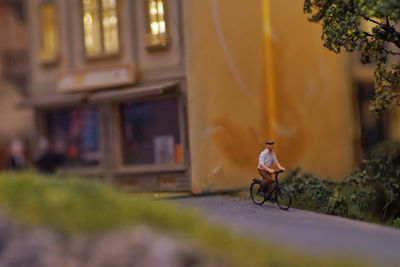 Man riding bicycle on street against buildings in city