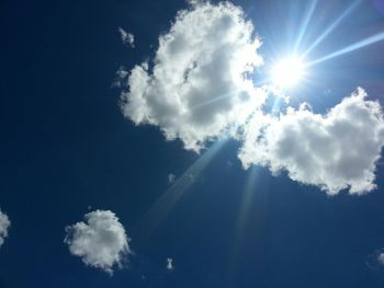 Low angle view of sun shining through clouds