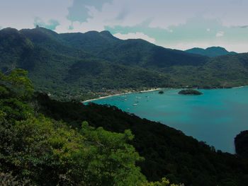 Scenic view of green mountains and sea against sky