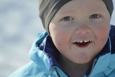 Close-up portrait of smiling boy standing outdoors during winter