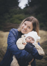 A woman with an infant is standing on the californian beach