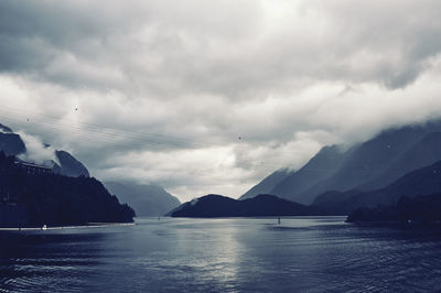 Scenic view of river and mountains against cloudy sky