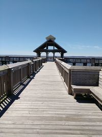 Wooden pier on sea against clear blue sky