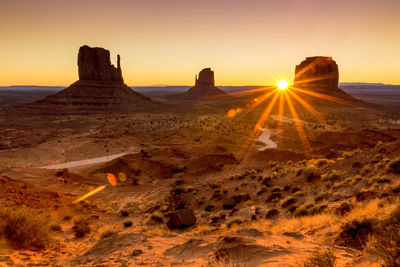 Rock formations on landscape against sunset sky