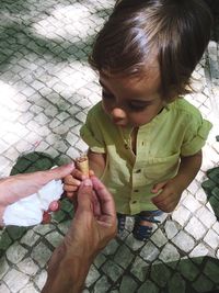 Cropped hands of person giving ice cream cone to boy