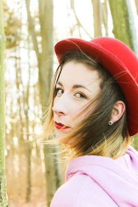 Close-up portrait of beautiful woman wearing red hat in forest