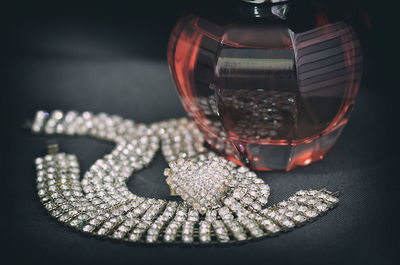 High angle view of necklace with perfume on table