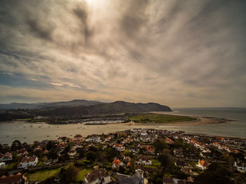 Town by sea against cloudy sky