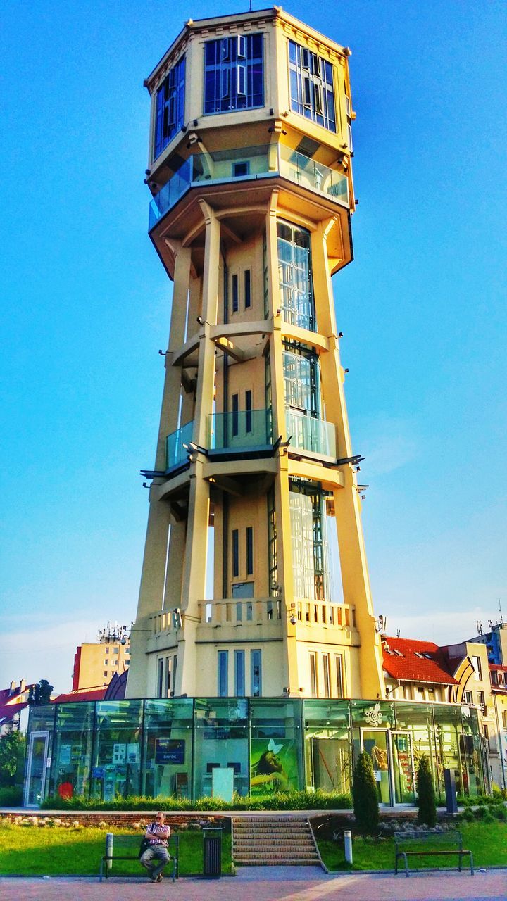 architecture, building exterior, built structure, clear sky, low angle view, blue, window, building, sunlight, facade, residential building, day, sky, city, residential structure, outdoors, exterior, incidental people, tower, no people