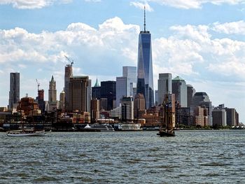 Buildings in front of river against cloudy sky in city