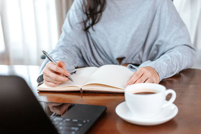 Midsection of businesswoman with diary on desk working in office