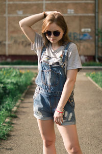 Woman with hand in hair standing on footpath