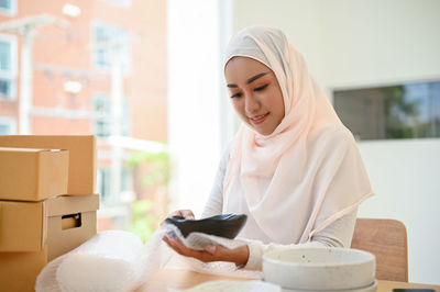 Young businesswoman in hijab packing parcels