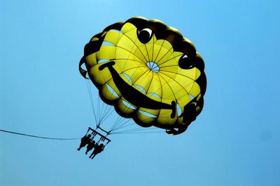 Low angle view of person paragliding against clear blue sky