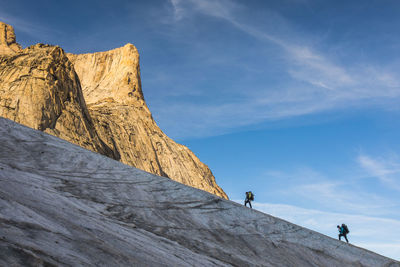 Low angle view of people on rock against sky